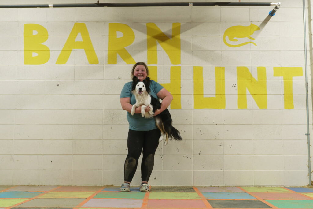 Rebecca and Peregrine showing off the Barn Hunt sign at Skybound Dog Training in Edmonton